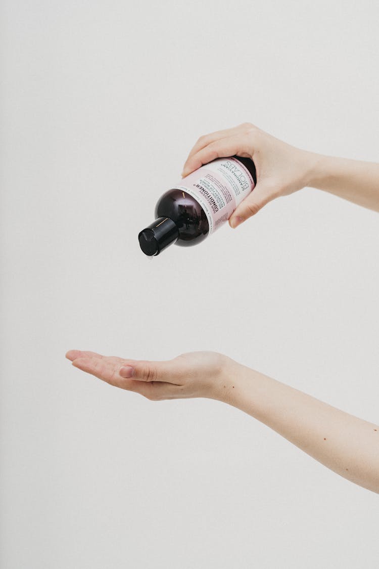 A Person Pouring Conditioner On Their Hand