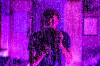 这幅富有创意的肖像画，通过雨水覆盖的玻璃和紫色灯光的倒影，展现了摄影师的视角