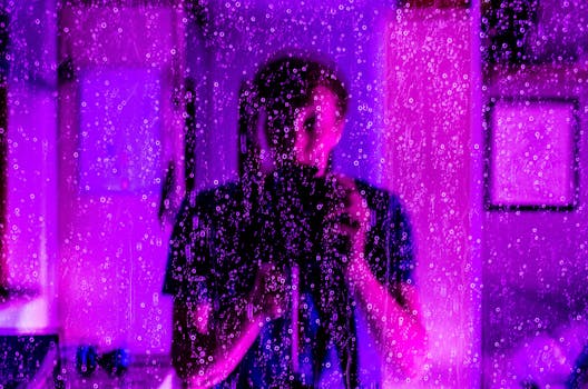 这幅富有创意的肖像画，通过雨水覆盖的玻璃和紫色灯光的倒影，展现了摄影师的视角