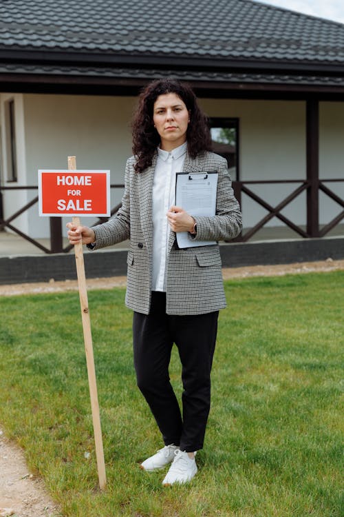 Woman Holding a Home For Sale Sign