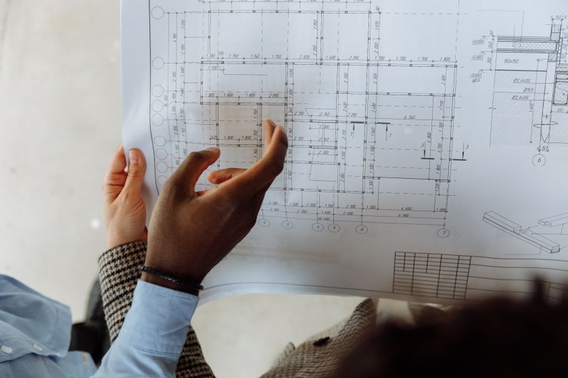 A detailed house plan being reviewed by hand