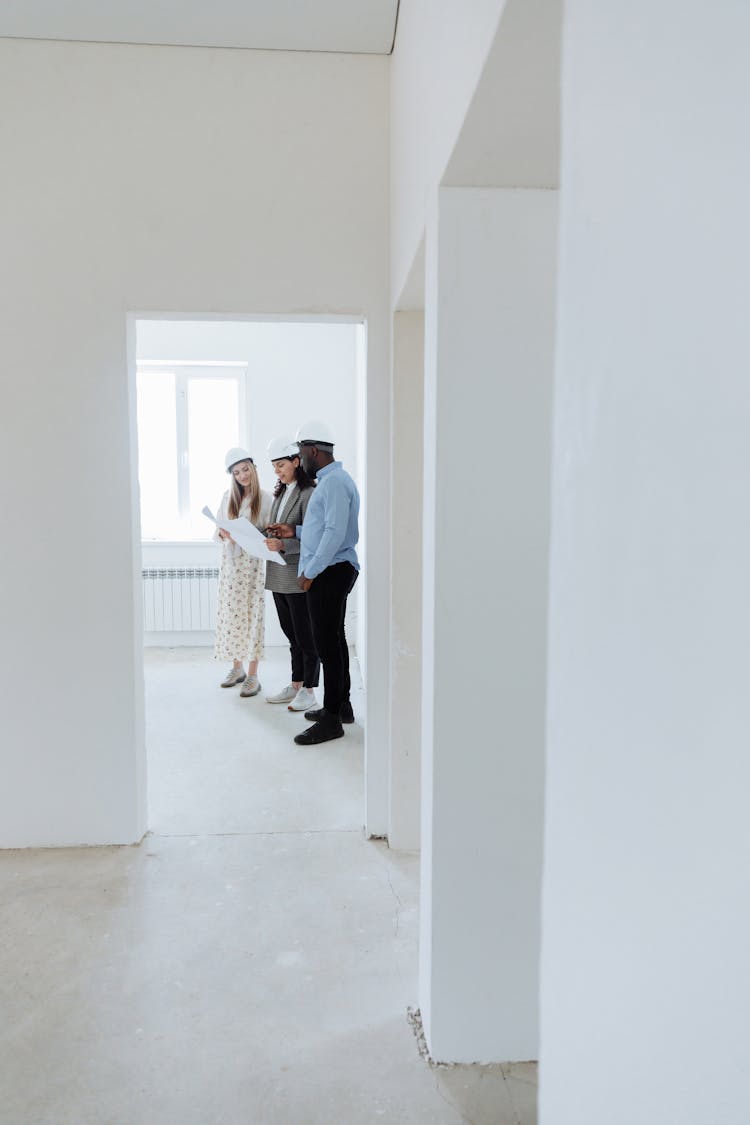 A Realtor Looking At A Floor Plan With A Couple