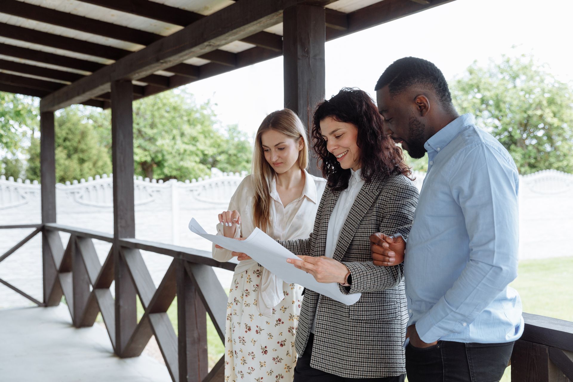 Group of professionals discussing plans on a porch, outdoors, with enthusiasm and teamwork spirit.