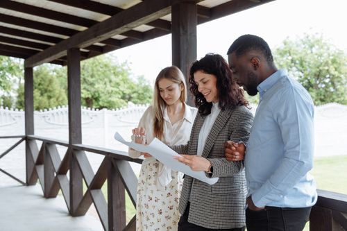 Free Group of professionals discussing plans on a porch, outdoors, with enthusiasm and teamwork spirit. Stock Photo