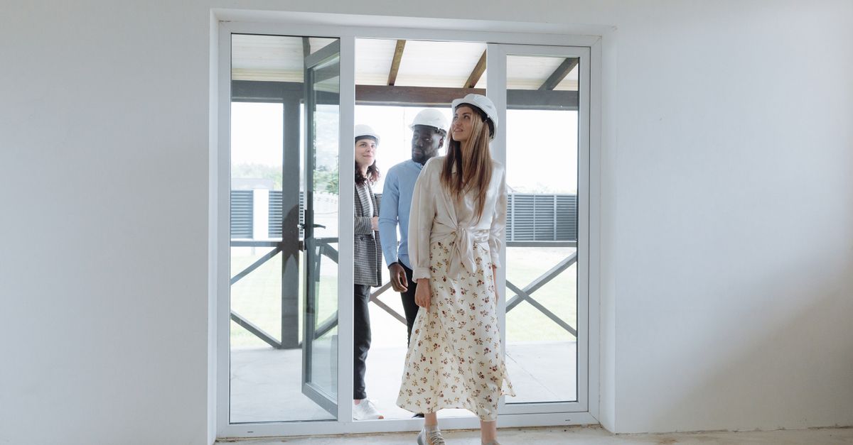 Group of architects walking through a bright new building, inspecting the interior space for construction evaluation.