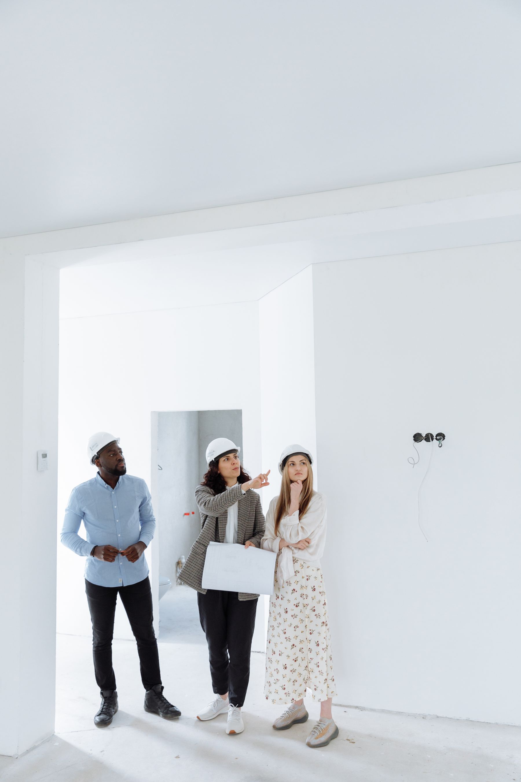 Asesora inmobiliaria recorriendo una propiedad en obra con sus clientes