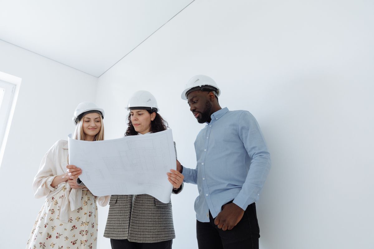 Group of professionals in hard hats examining construction blueprints