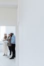 People Holding a Piece of Paper while Standing Near White Walls