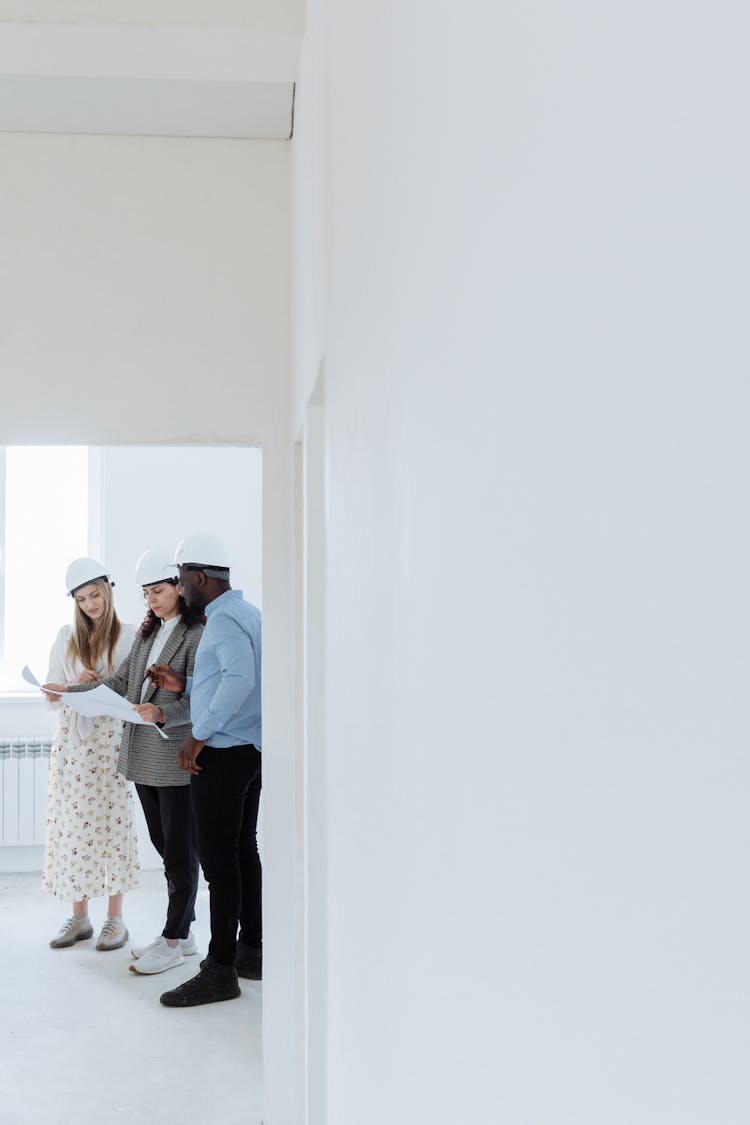 People Holding A Piece Of Paper While Standing Near White Walls