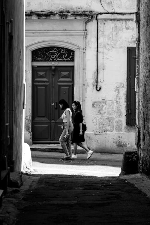 
A Grayscale of Women Walking on an Alley