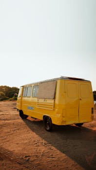 Bright yellow van parked on a dirt road under a clear sky in Antalya, capturing a vintage travel vibe.