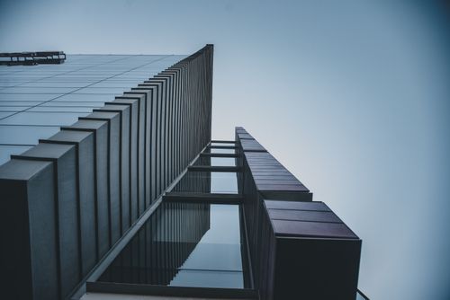 Free Low-angle shot of a modern skyscraper with sleek lines and glass facade against a blue sky. Stock Photo