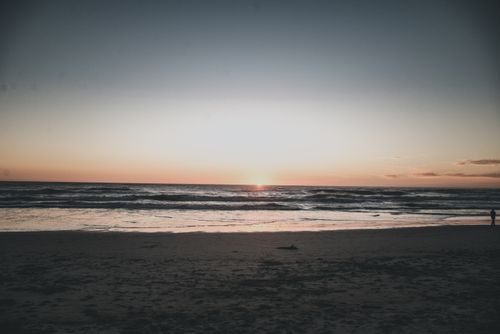 Free A peaceful sunset on a quiet beach with gentle waves meeting the shore. Stock Photo