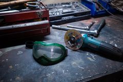 A workshop scene with tools, a grinder, and safety goggles on a workbench.