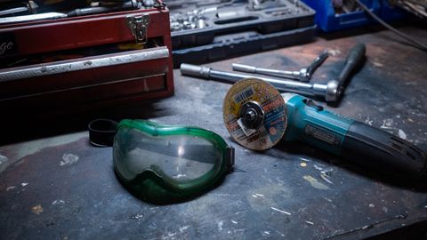 A workshop scene with tools, a grinder, and safety goggles on a workbench.