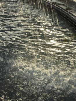 Close-up of water splashing in a fountain, capturing the serene flow in sunlight.