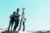 三名男子穿着休闲装，在户外阳光明媚的一天中微笑着互动