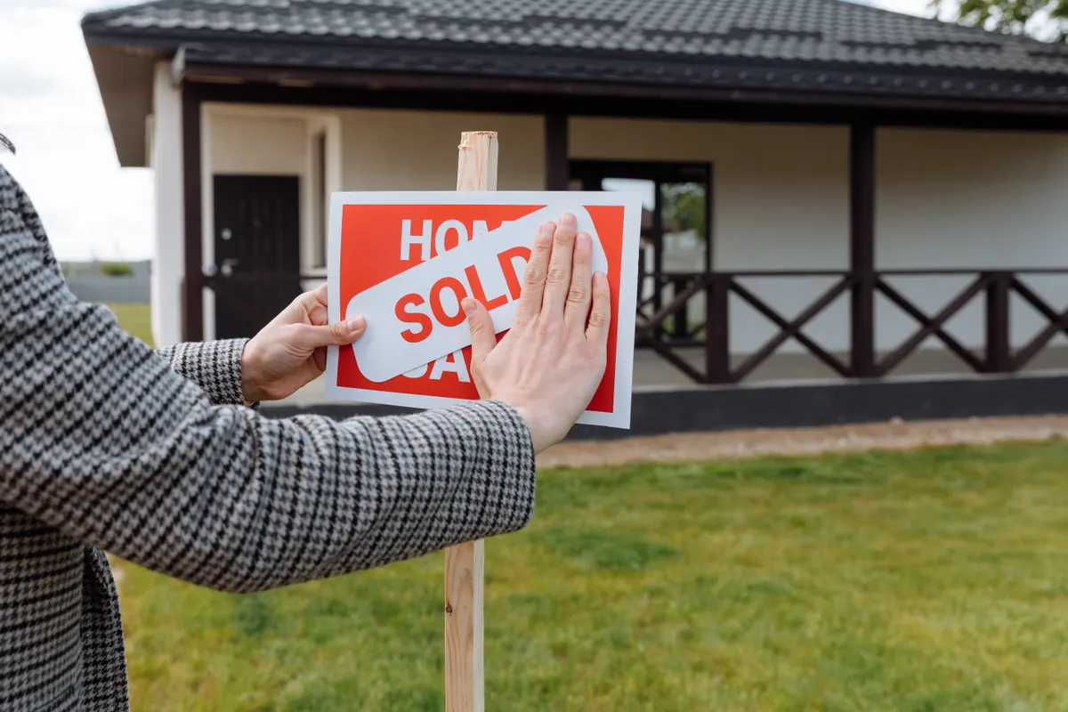 Sold sticker placed on a home sale sign — illustrating deciding when to buy