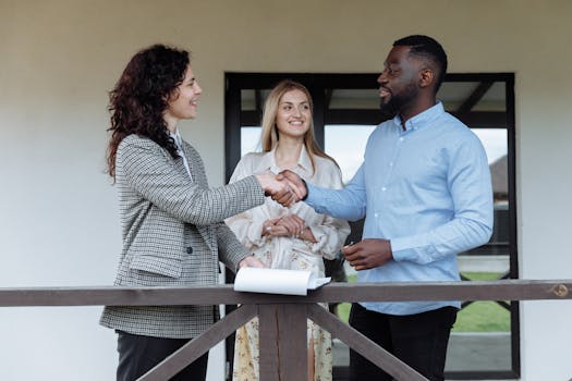 Three adults sealing a real estate deal with a handshake on a porch.