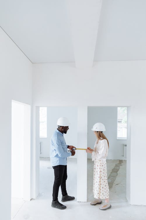 Free A Man and Woman Having Conversation while Measuring the Wall Stock Photo