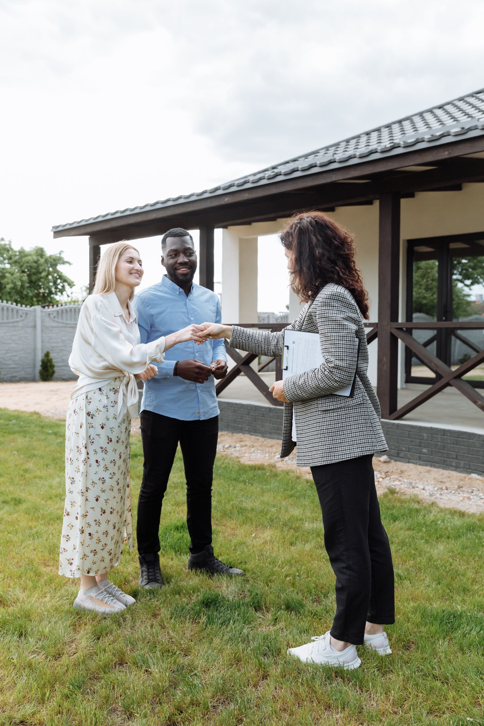 Real estate agent greeting clients outside a home