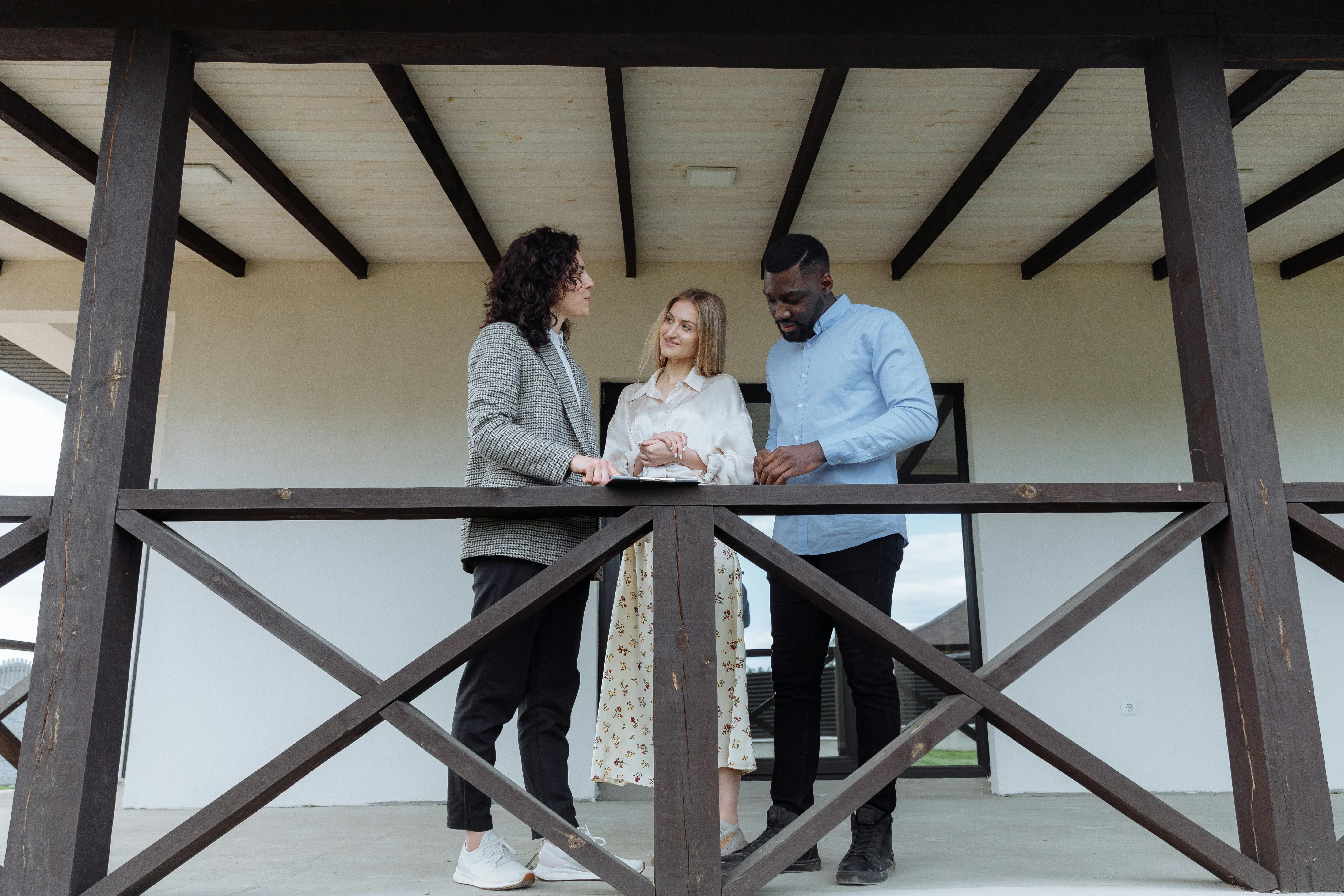 Real estate agent discussing property features with a couple on a balcony.