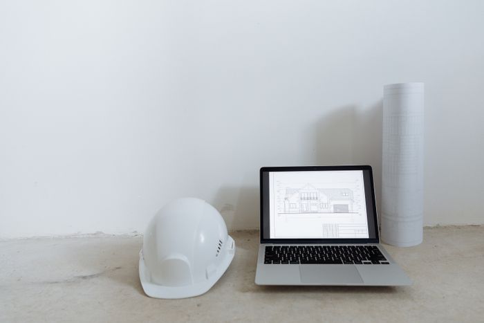 Laptop, hard hat and blueprints set up for design coordination