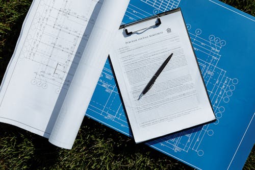 Free Contract on Clipboard and Blueprints Stock Photo