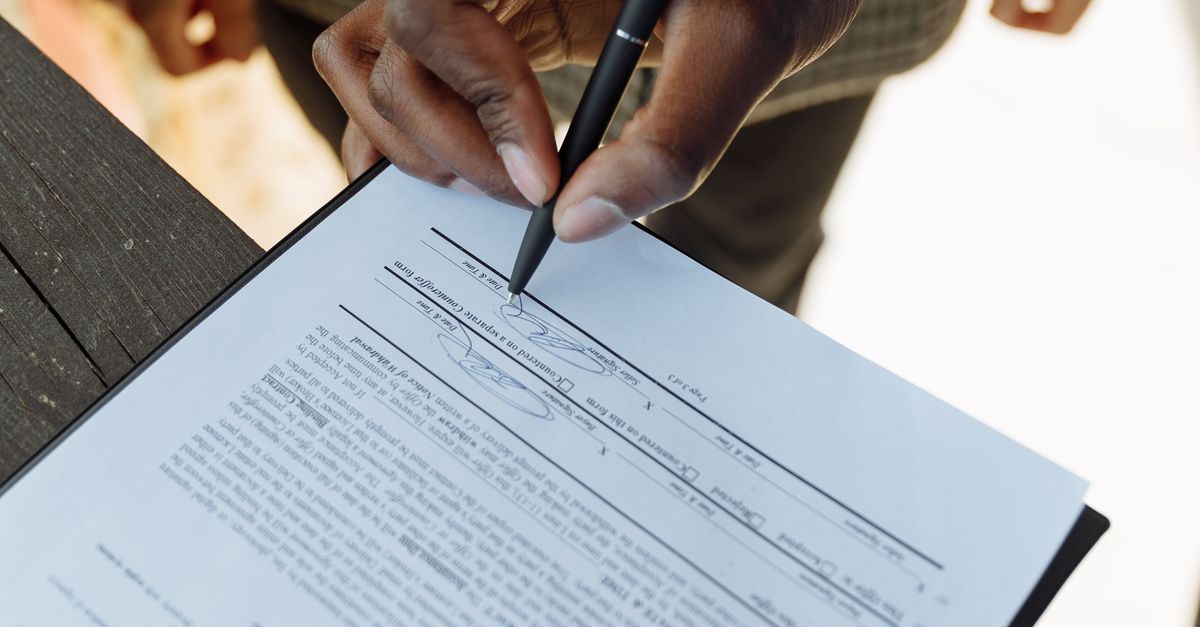 Close-up of a person signing a contract with a pen