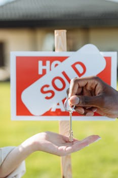 Key exchange in front of a sold sign, symbolizing successful real estate transaction.