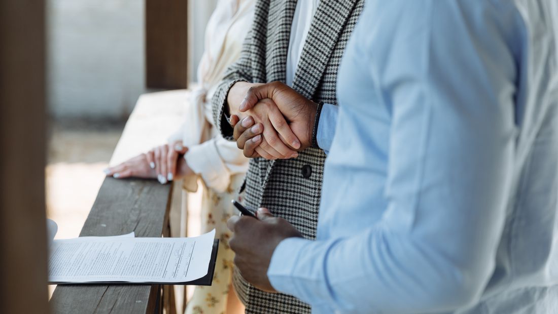 Une poignée de main entre un courtier et un client au-dessus d’un contrat