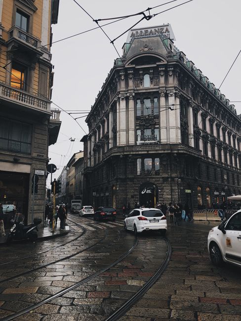 A rainy street scene in Milan, capturing historic architecture and urban life.