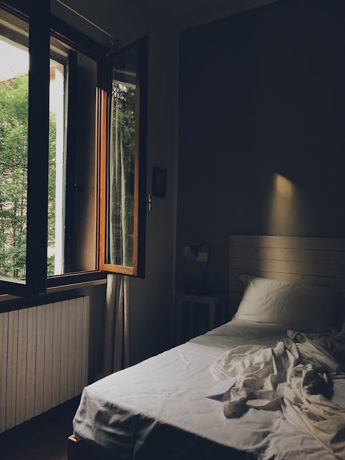 Bed with White Linen Beside a Window