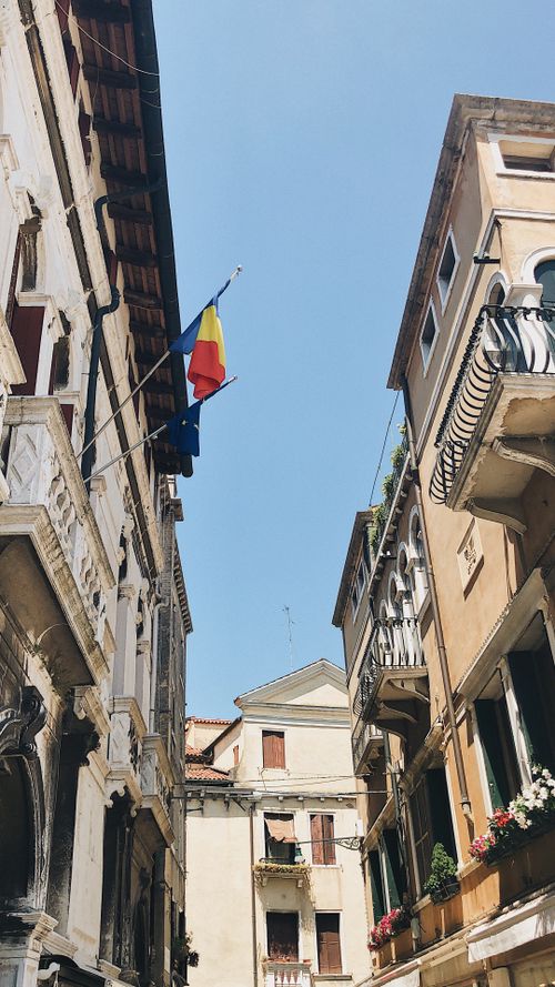 Free A beautiful European alley with flags and Gothic architectural details under a clear blue sky. Stock Photo