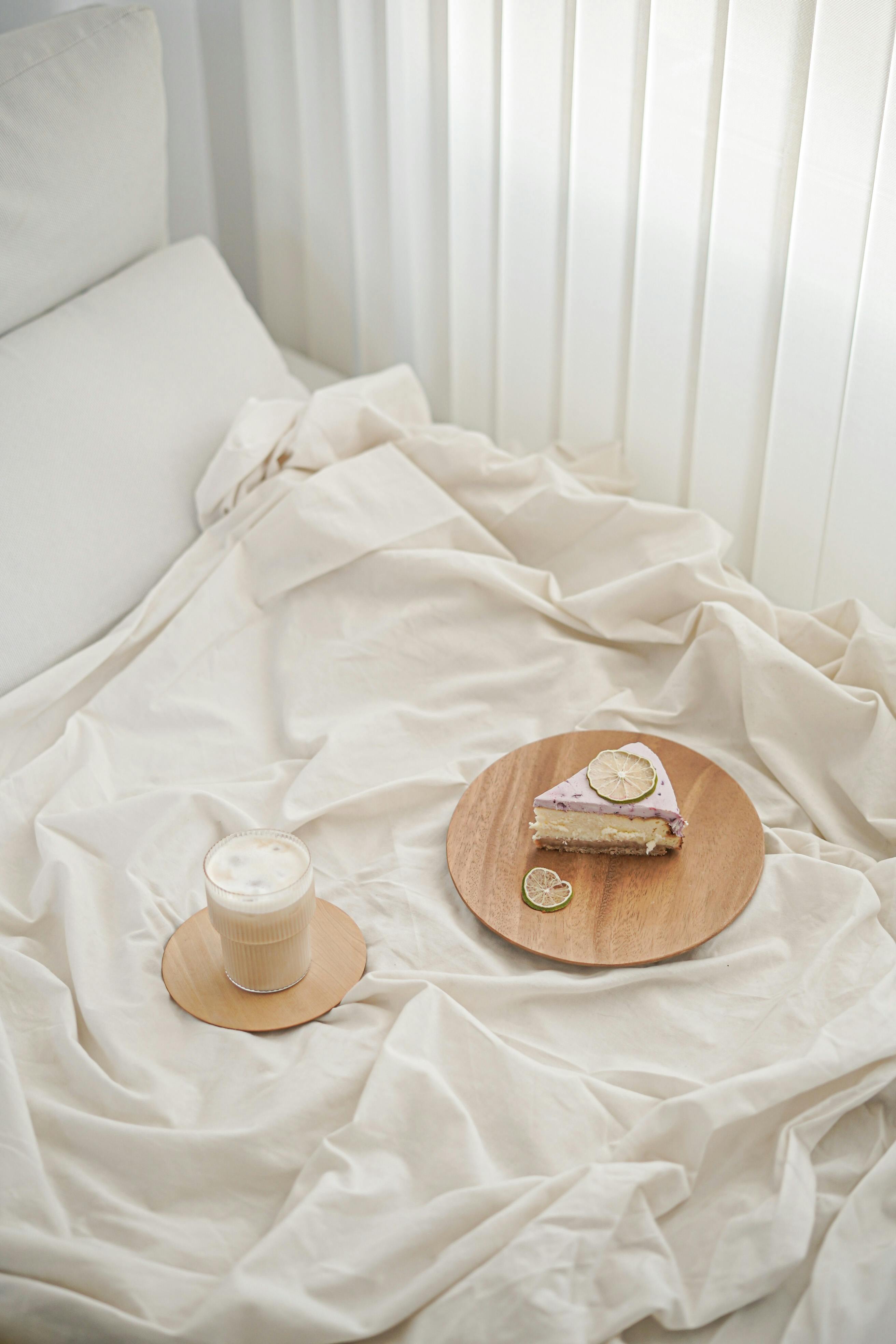 Appetizing cheesecake slice and coffee on a cozy bed setting, perfect for breakfast in bed ambiance.