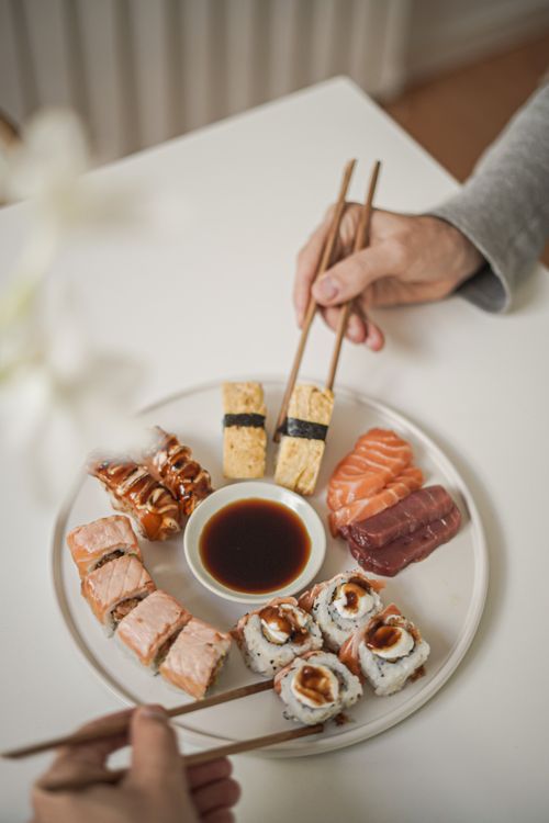 Free A beautifully arranged sushi platter with various types and chopsticks on a table. Stock Photo