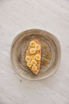High-angle shot of banana slices on peanut butter toast on a plate.