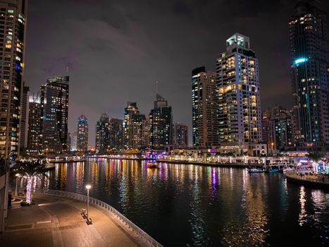 A stunning night view of Dubai Marina with illuminated skyscrapers reflecting on the water.