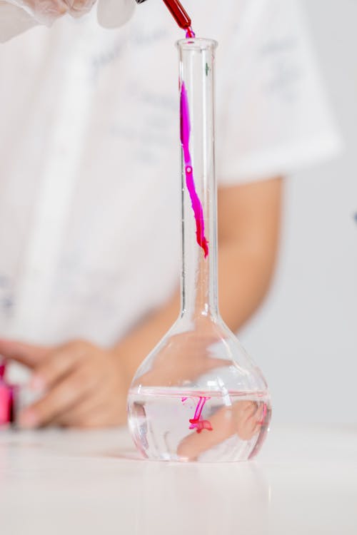 Person Holding Clear Glass Bottle With Pink Straw