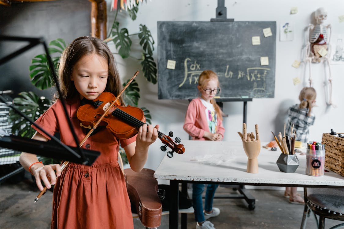 Free A Little Girl Playing the Violin in a Classroom Stock Photo