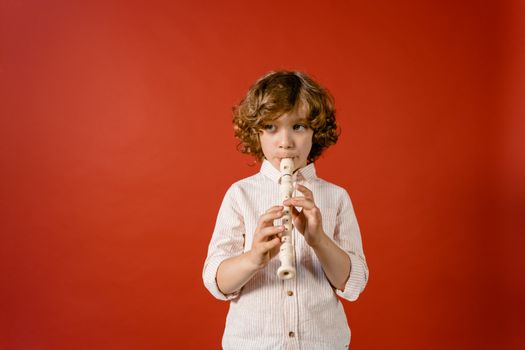 Little Boy Playing His Flute on Red Background