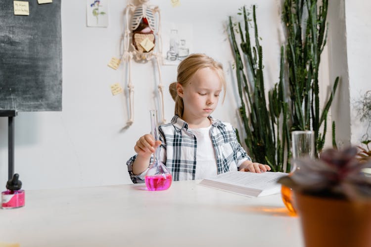 A Smart Girl Reading A Book While Doing A Science Experiment