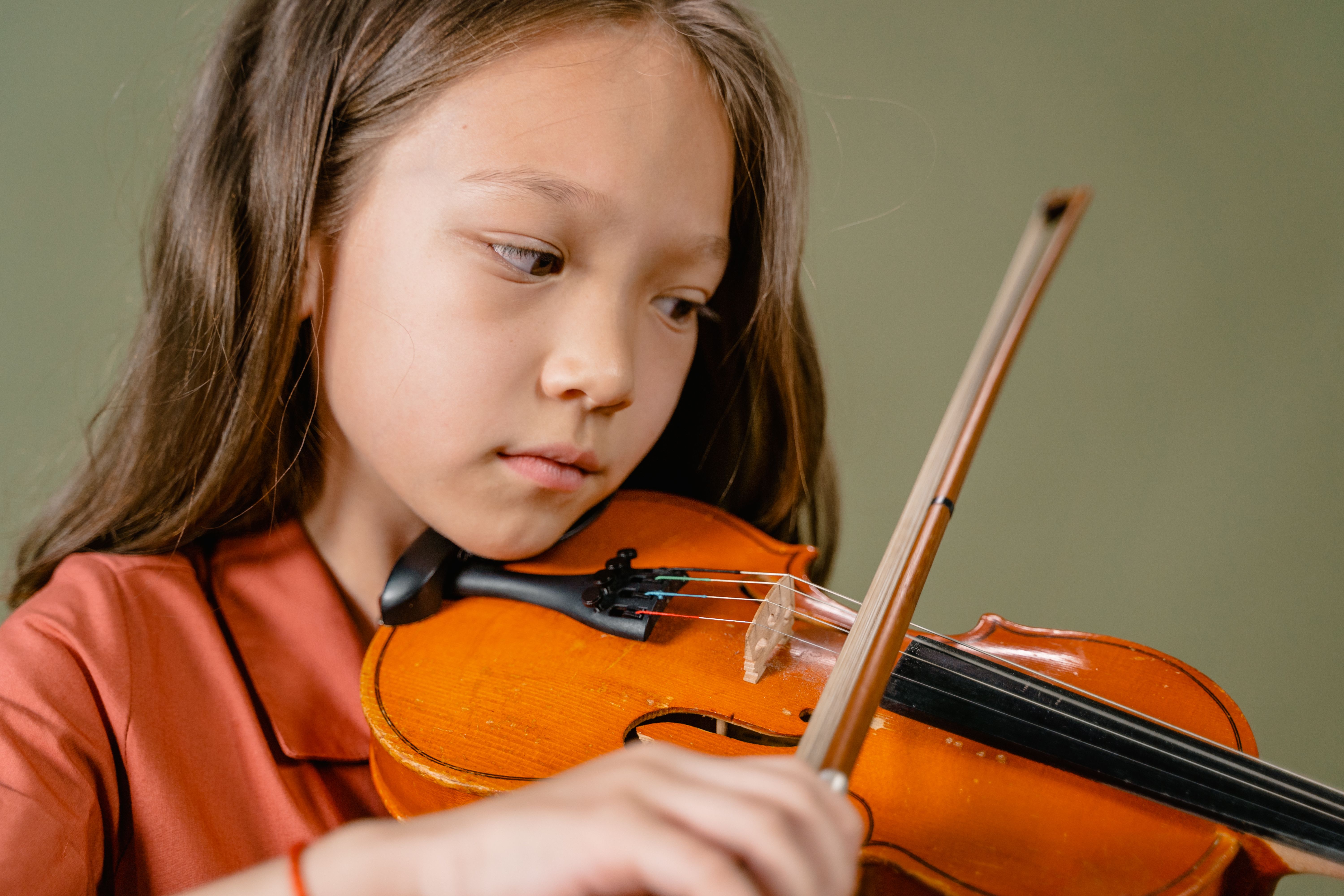 A young girl intently playing the violin, showcasing her musical skills and passion.