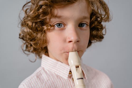 Close-Up Photo of a Boy Playing His Flute