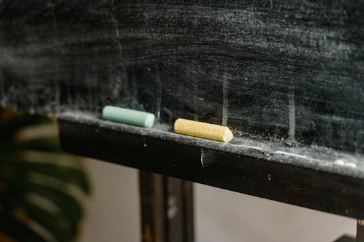 Detailed shot of colored chalk pieces on a dusty blackboard ledge.