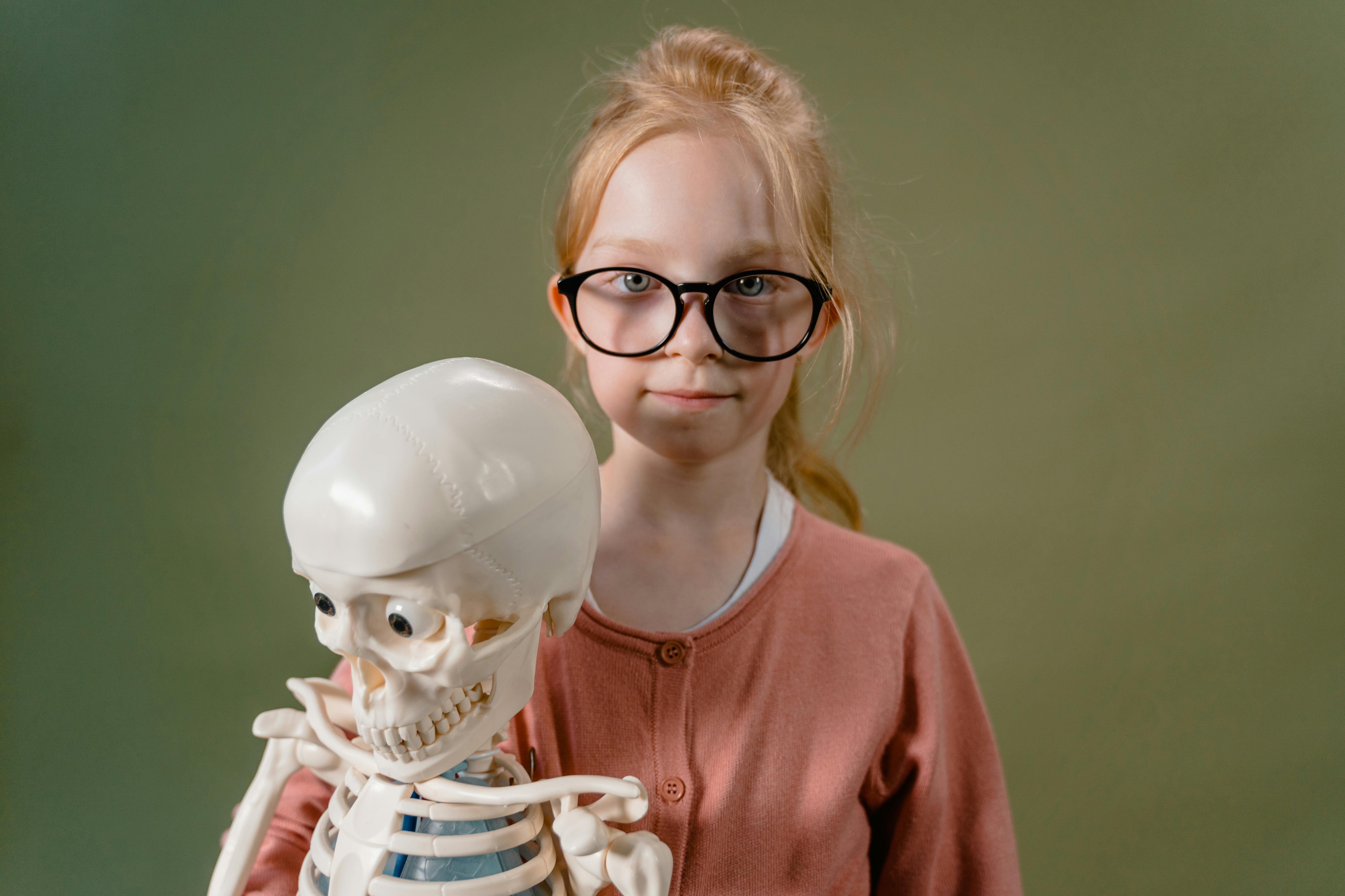 a girl with eyeglasses holding a skeleton