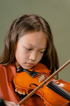 Close-up of a young girl playing the violin with concentration.
