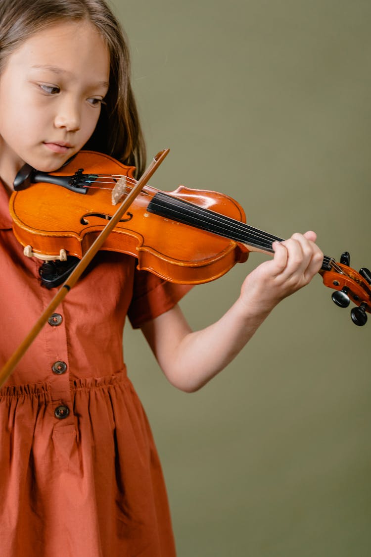 A Girl In Orange Dress Playing Violin