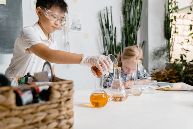 A Boy Pouring Chemical On A Flask 