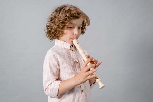 Child with curly hair playing a wooden recorder indoors, reflecting concentration.
